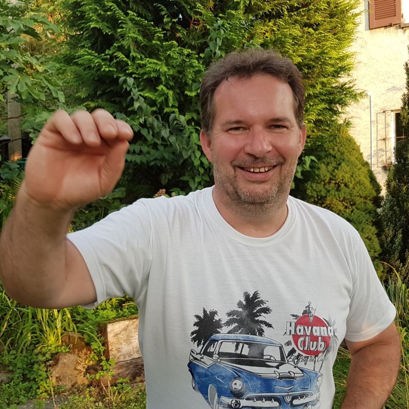 SalaRica Tanzschule Zürich Practicalehrer Wolfgang Mann mit kurzen Haaren mit weissem T-Shirt mit Havana club Aufschrift im Garten, welcher mit der Hand winkt