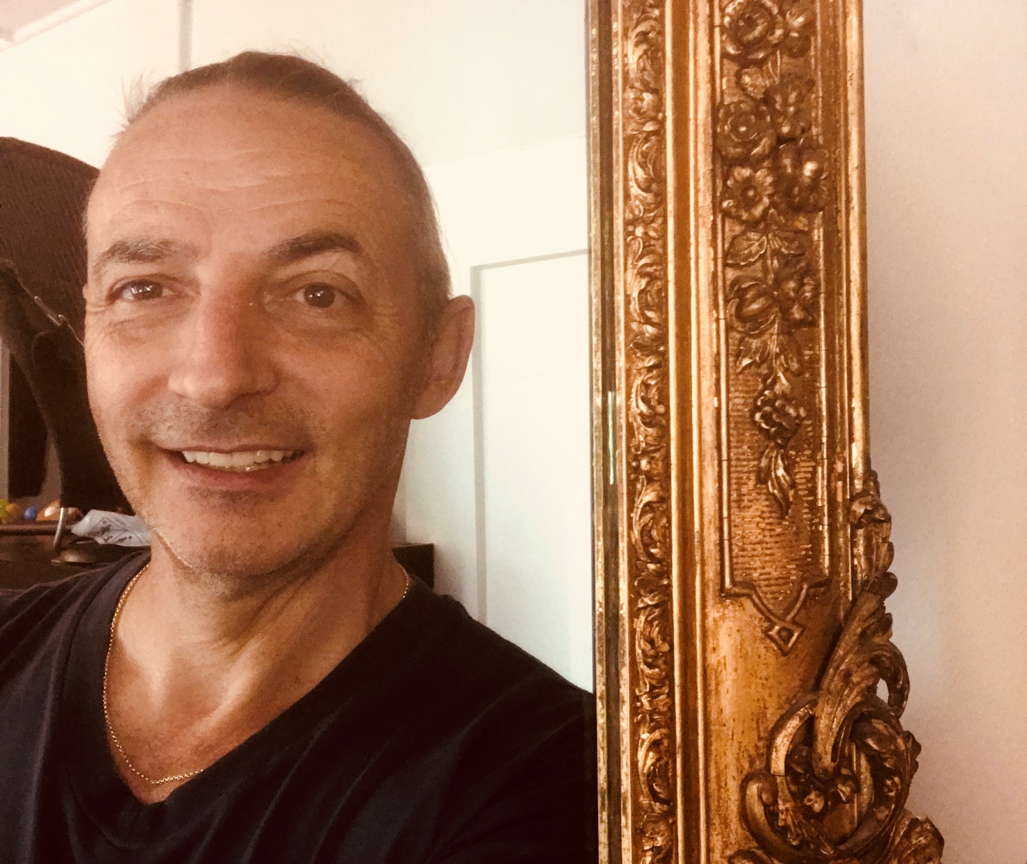 Mann im Spiegelbild von einem Spiegel mit goldenem massiven Rand.